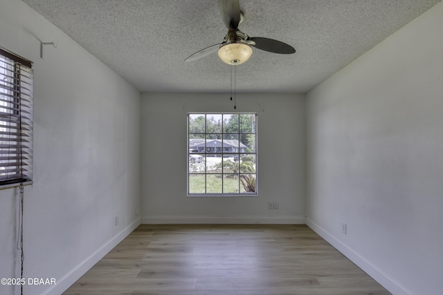 unfurnished room featuring baseboards, a textured ceiling, ceiling fan, and light wood finished floors