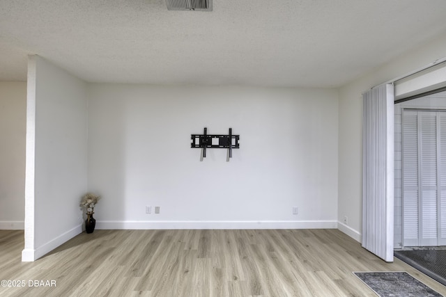 unfurnished dining area with baseboards, a textured ceiling, wood finished floors, and visible vents