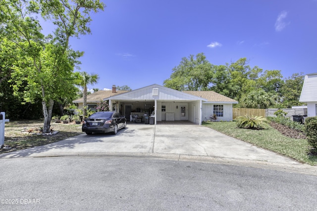 view of front of home featuring concrete driveway, fence, and a carport