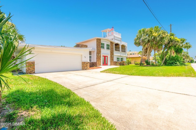 46 Oceanview Ave, Ponce Inlet, FL 32127 - view of front of home with an attached garage, concrete driveway, a front lawn, stone siding, and french doors