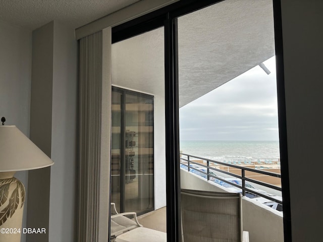 balcony featuring a view of the beach and a water view