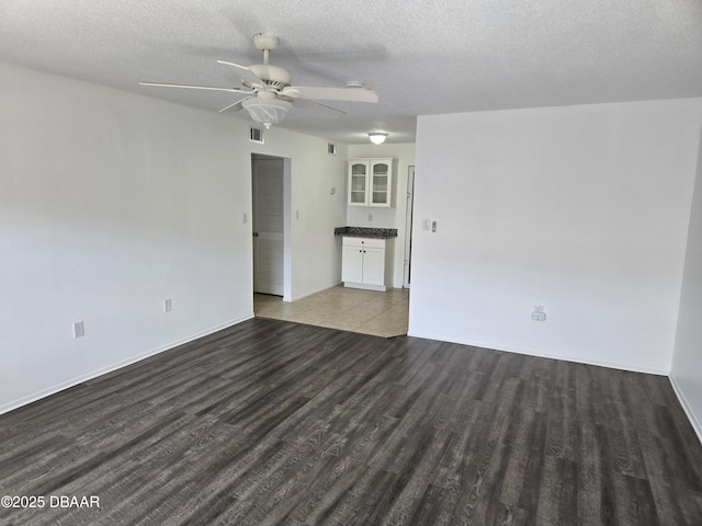 empty room featuring dark wood-type flooring, ceiling fan, and a textured ceiling