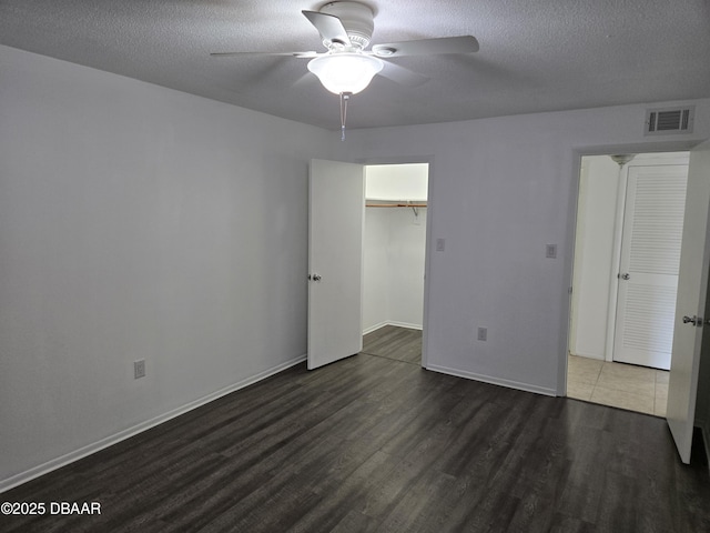 unfurnished bedroom with ceiling fan, dark hardwood / wood-style floors, a textured ceiling, and a closet