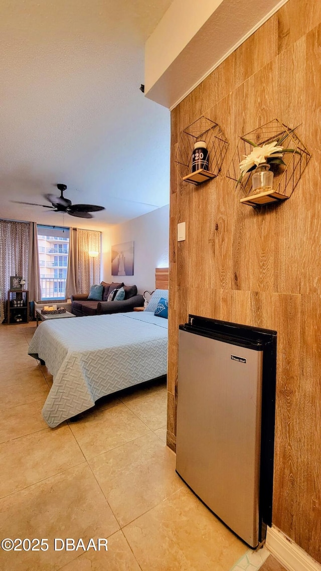 2043 S Atlantic Ave Unit 415, Daytona Beach, FL 32118 - bedroom featuring freestanding refrigerator, light tile patterned floors, wood walls, and ceiling fan