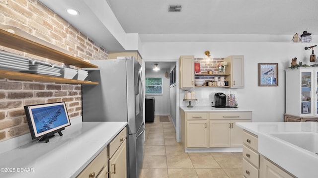 156 Holly Hill Ct, New Smyrna Beach, FL 32168 - kitchen featuring open shelves, freestanding refrigerator, light countertops, light tile patterned floors, and brick wall