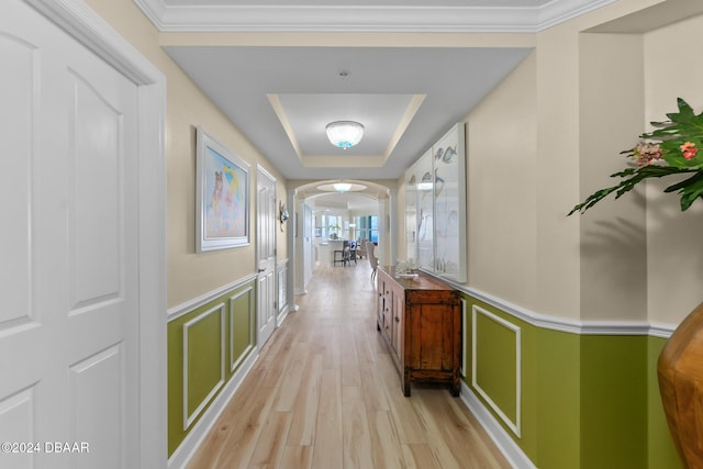 hallway featuring a raised ceiling, crown molding, and light hardwood / wood-style floors