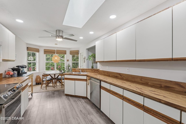 113 Bridgehaven Dr, Palm Coast, FL 32137 - kitchen with wooden counters, stainless steel appliances, light wood-style flooring, white cabinets, and recessed lighting