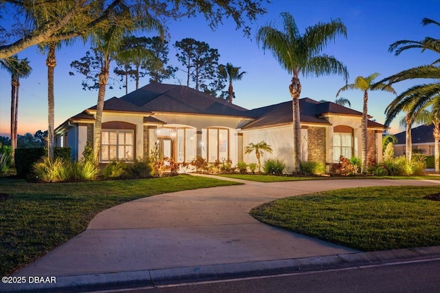 1305 Dovercourt Ln, Ormond Beach, FL 32174 - mediterranean / spanish-style house with stucco siding, curved driveway, and a yard