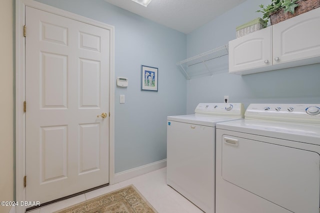 clothes washing area featuring cabinets, light tile patterned floors, and washer and dryer