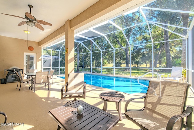 view of swimming pool with ceiling fan, a patio, and glass enclosure