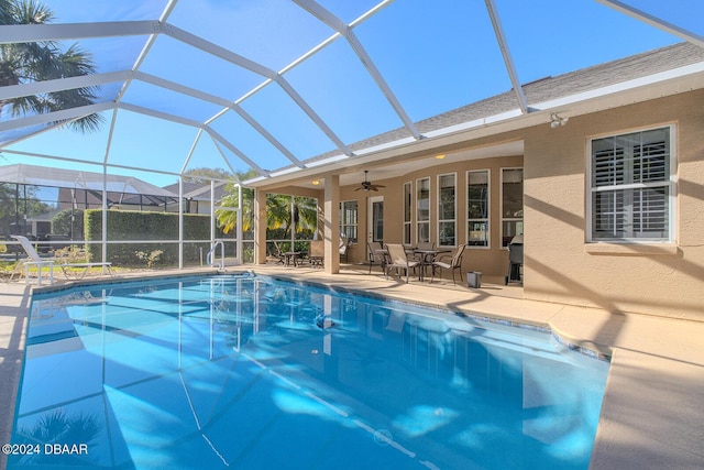 view of pool with a patio, glass enclosure, and ceiling fan