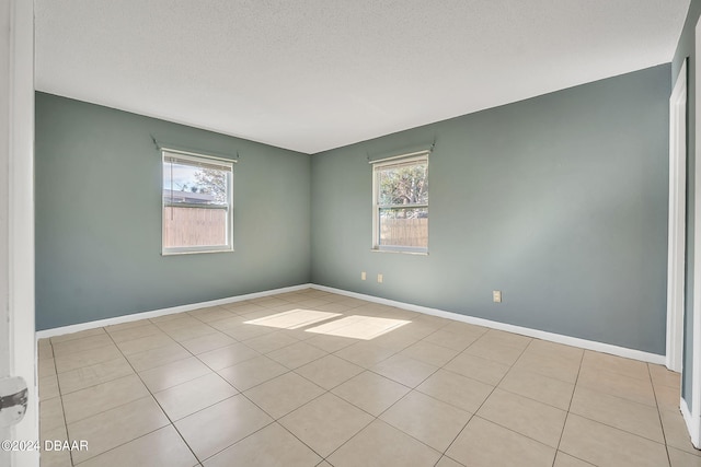 tiled spare room with plenty of natural light and a textured ceiling