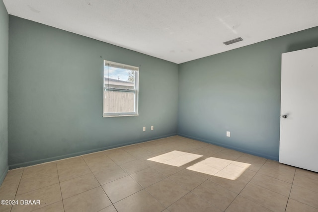 tiled spare room featuring a textured ceiling