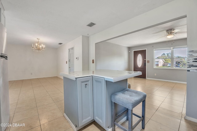 kitchen with hanging light fixtures, a kitchen bar, light tile patterned flooring, and a center island