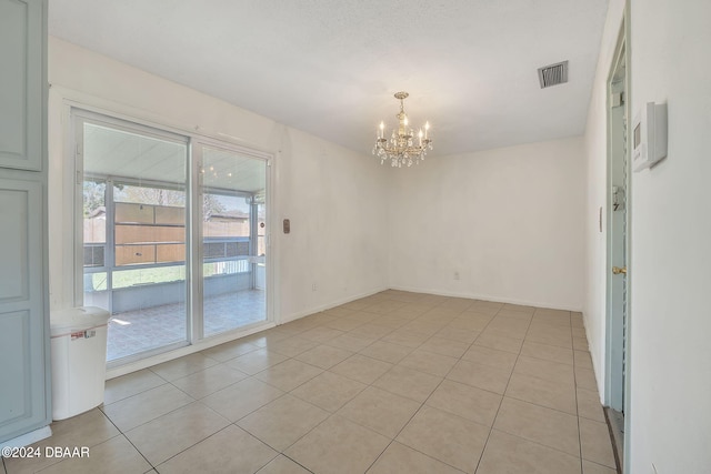 tiled empty room featuring a chandelier