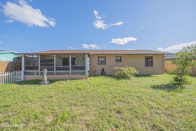 back of property with a sunroom and a yard