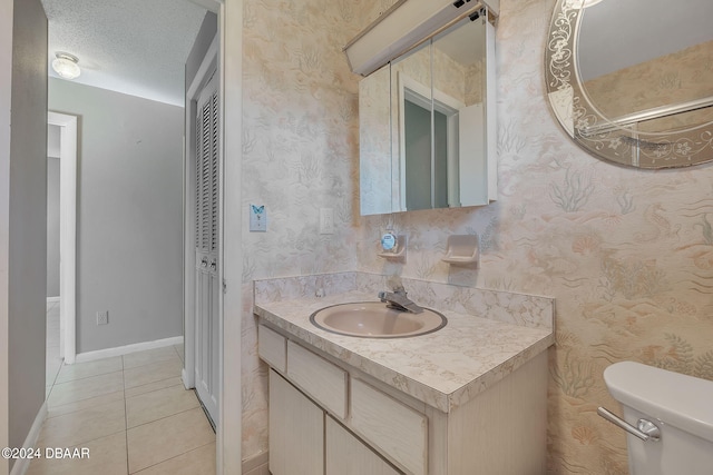 bathroom with toilet, vanity, a textured ceiling, and tile patterned flooring