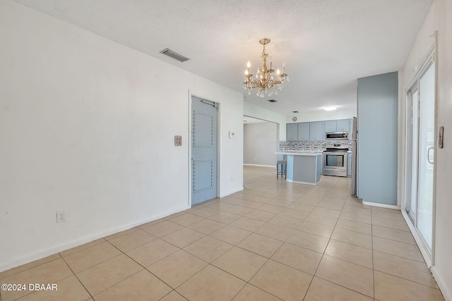 kitchen featuring a textured ceiling, light tile patterned floors, backsplash, and appliances with stainless steel finishes