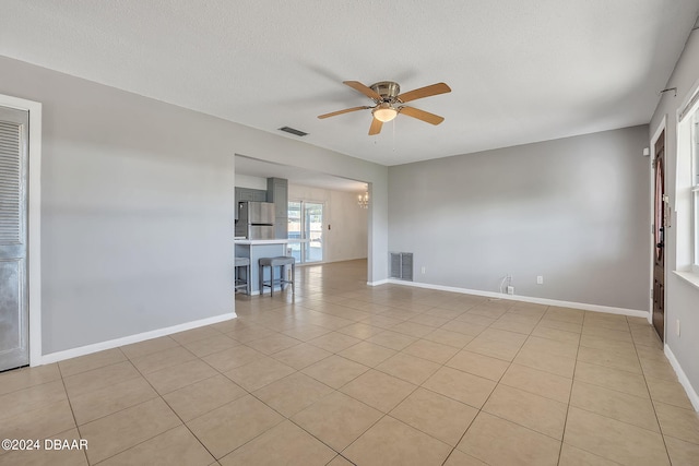 unfurnished room with light tile patterned flooring, ceiling fan with notable chandelier, and a textured ceiling