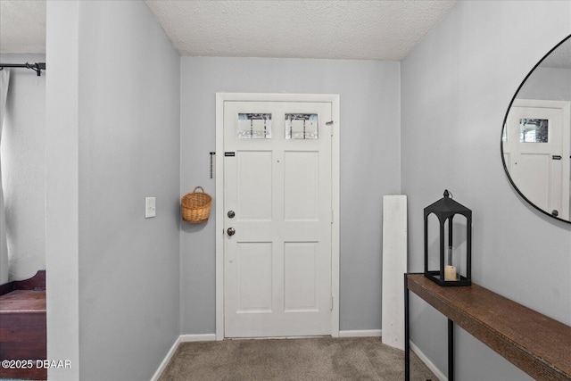 foyer entrance with a textured ceiling, carpet, and baseboards