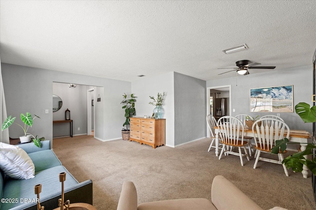 carpeted living room featuring a ceiling fan, visible vents, a textured ceiling, and baseboards