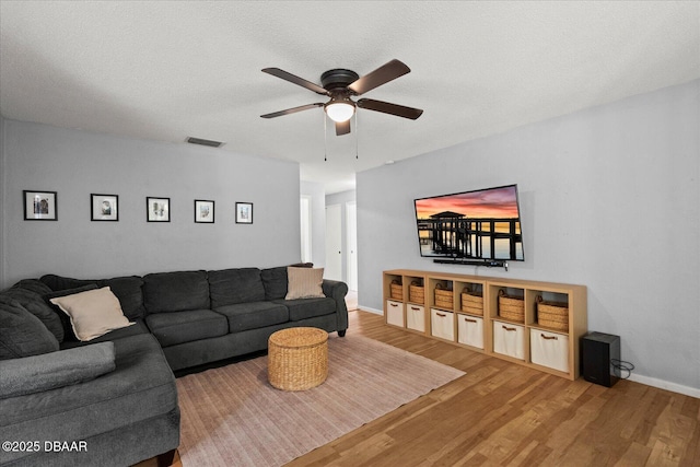living area with wood finished floors, visible vents, ceiling fan, and a textured ceiling