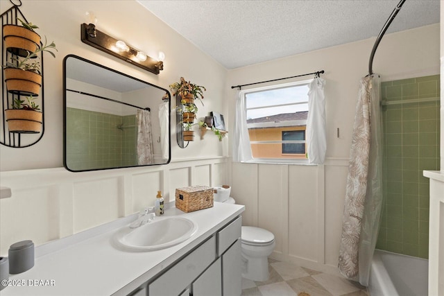 full bath with a textured ceiling, wainscoting, and a decorative wall