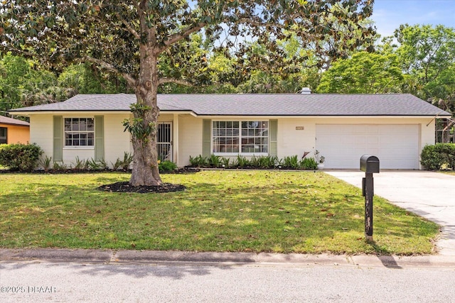 single story home featuring a front yard, driveway, and an attached garage