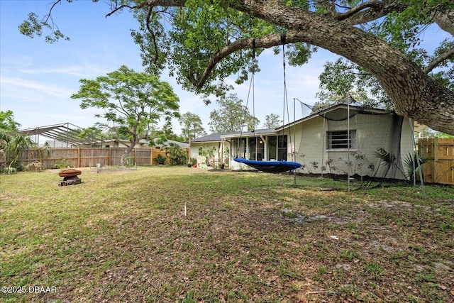 view of yard with an outdoor fire pit, a sunroom, and a fenced backyard