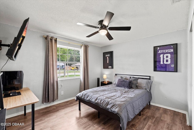bedroom with a textured ceiling, ceiling fan, wood finished floors, and baseboards