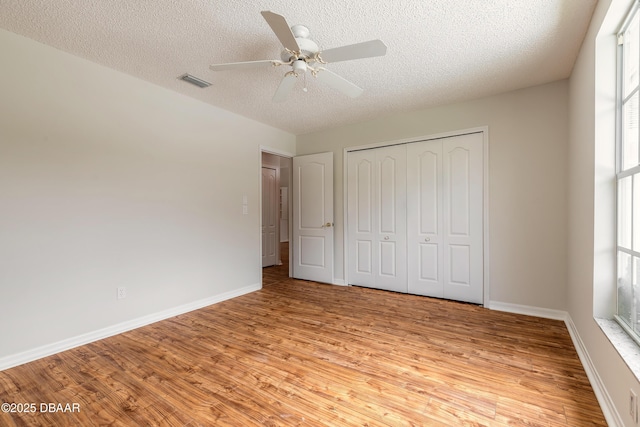 19 Meadow Ridge Vw, Ormond Beach, FL 32174 - unfurnished bedroom featuring a textured ceiling, multiple windows, light wood finished floors, a closet, and a ceiling fan