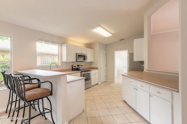19 Meadow Ridge Vw, Ormond Beach, FL 32174 - kitchen with appliances with stainless steel finishes, a peninsula, a kitchen breakfast bar, white cabinetry, and vaulted ceiling