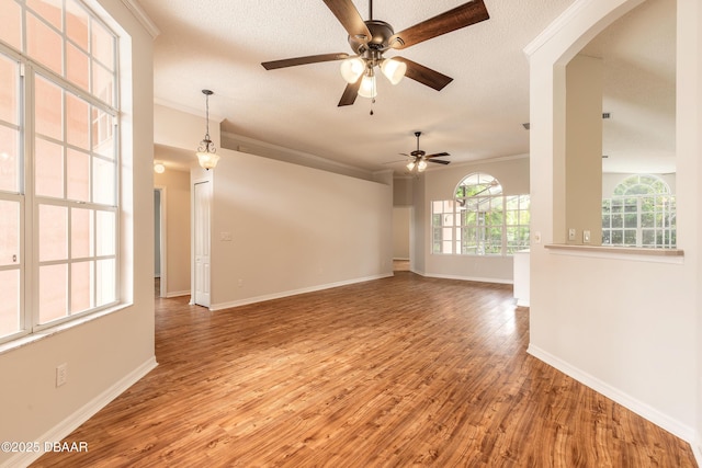 19 Meadow Ridge Vw, Ormond Beach, FL 32174 - empty room featuring light wood-style floors, a ceiling fan, ornamental molding, arched walkways, and a textured ceiling