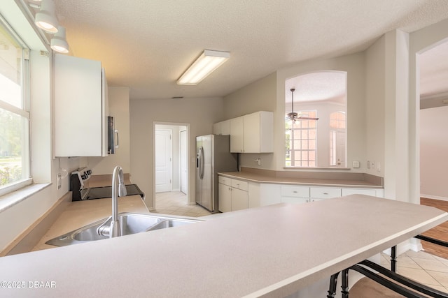 19 Meadow Ridge Vw, Ormond Beach, FL 32174 - kitchen featuring appliances with stainless steel finishes, arched walkways, a textured ceiling, light countertops, and white cabinetry