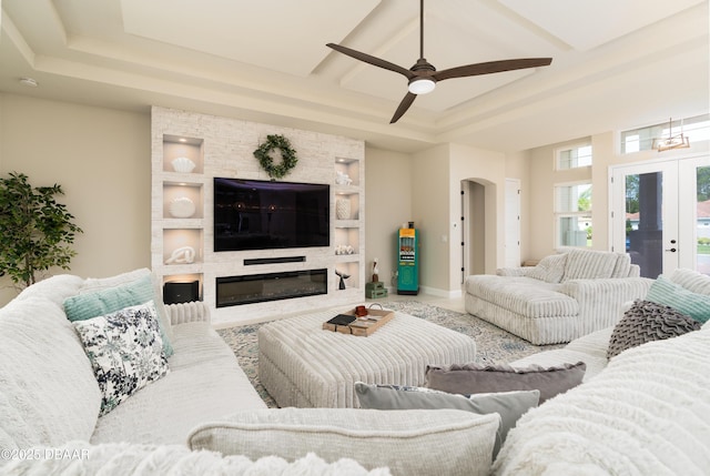 150 Portofino Blvd, New Smyrna Beach, FL 32168 - living room with a ceiling fan, arched walkways, a raised ceiling, a fireplace, and french doors