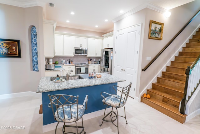 kitchen with light stone countertops, appliances with stainless steel finishes, white cabinetry, sink, and backsplash