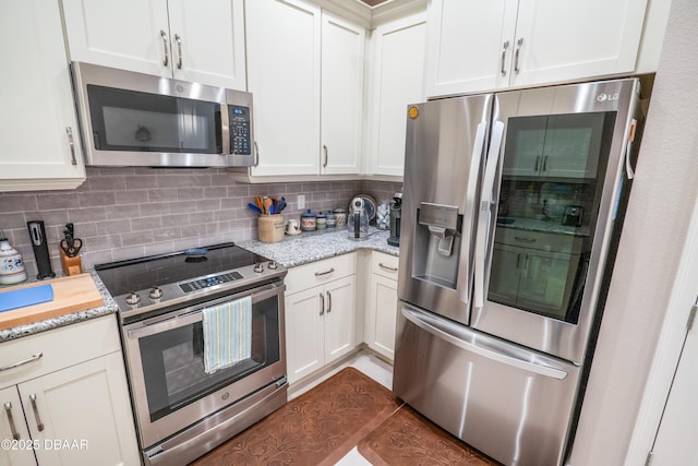 kitchen featuring white cabinetry, light stone countertops, backsplash, and appliances with stainless steel finishes