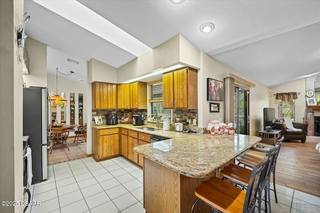 kitchen with lofted ceiling, a peninsula, a sink, and freestanding refrigerator