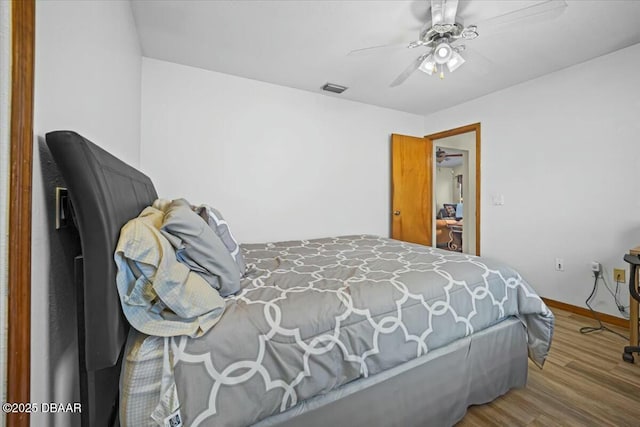 bedroom featuring visible vents, ceiling fan, baseboards, and wood finished floors