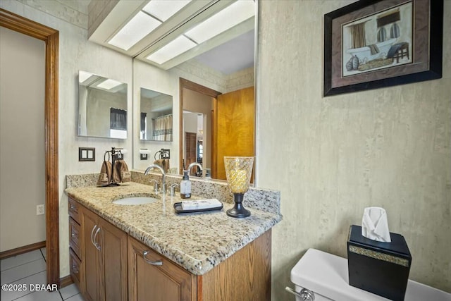 half bath with toilet, a skylight, tile patterned flooring, and vanity