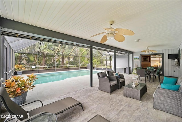 pool with a lanai, a patio area, outdoor lounge area, and a ceiling fan