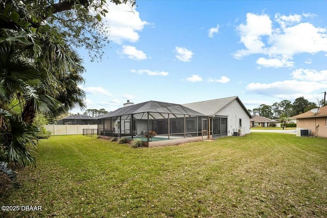 back of house featuring a lanai, fence, a yard, an outdoor pool, and a chimney