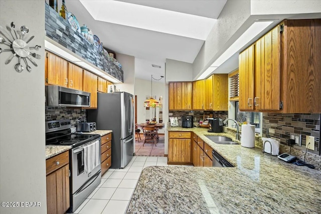 kitchen featuring light tile patterned floors, stainless steel appliances, a sink, brown cabinets, and tasteful backsplash