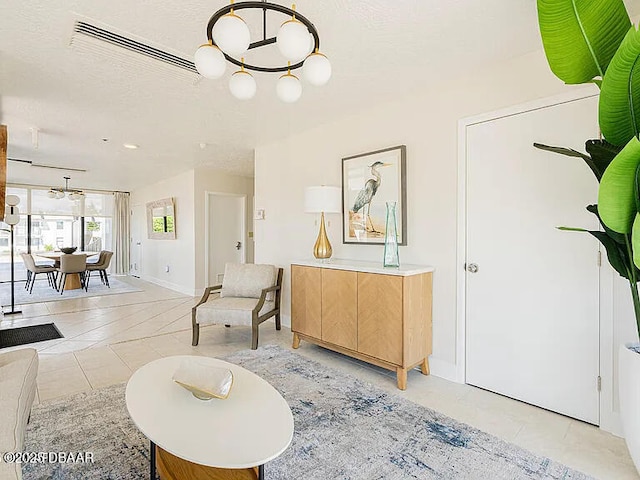 interior space with a chandelier, a textured ceiling, light tile patterned flooring, visible vents, and baseboards