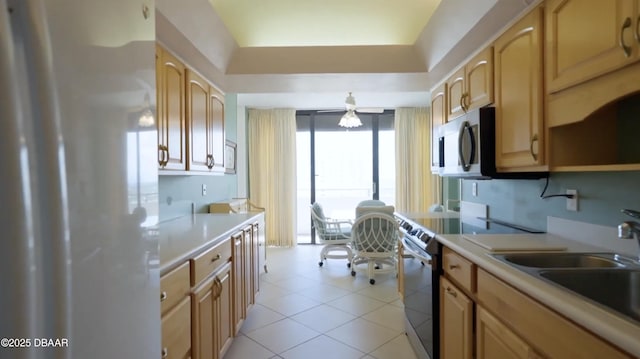 kitchen with appliances with stainless steel finishes, light countertops, a sink, and a raised ceiling