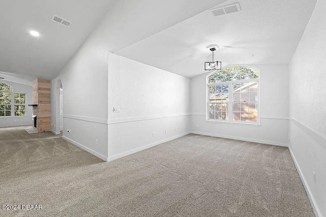 carpeted empty room featuring a wealth of natural light and lofted ceiling