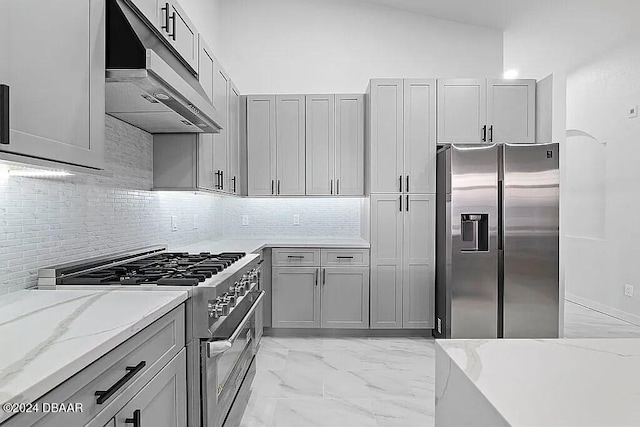 kitchen with gray cabinets, light stone countertops, vaulted ceiling, and appliances with stainless steel finishes