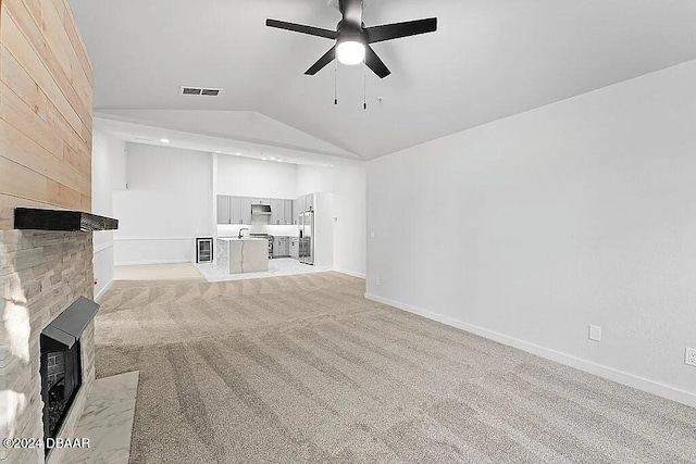 unfurnished living room with light carpet, a large fireplace, ceiling fan, and lofted ceiling