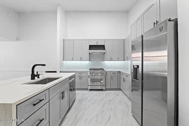 kitchen featuring gray cabinets, sink, stainless steel appliances, and range hood