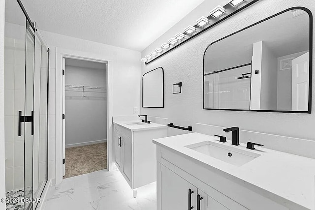 bathroom with vanity, an enclosed shower, and a textured ceiling